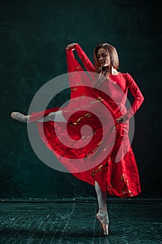 Ballerina posing in pointe shoes at black wooden pavilion