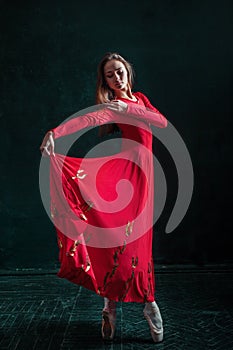 Ballerina posing in pointe shoes at black wooden pavilion