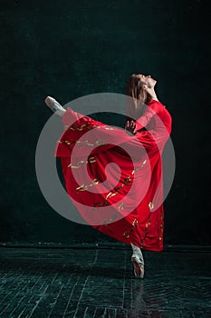 Ballerina posing in pointe shoes at black wooden pavilion