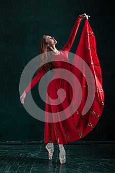 Ballerina posing in pointe shoes at black wooden pavilion