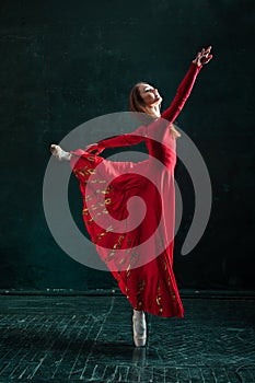 Ballerina posing in pointe shoes at black wooden pavilion