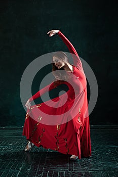 Ballerina posing in pointe shoes at black wooden pavilion