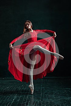 Ballerina posing in pointe shoes at black wooden pavilion