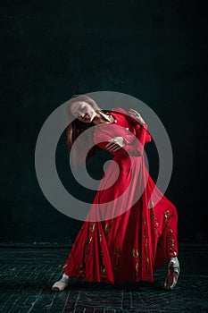 Ballerina posing in pointe shoes at black wooden pavilion