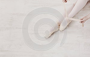 Ballerina puts on pointe ballet shoes, graceful legs