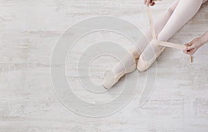 Ballerina puts on pointe ballet shoes, graceful legs