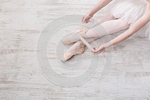 Ballerina puts on pointe ballet shoes, graceful legs