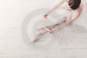 Ballerina puts on pointe ballet shoes, graceful legs