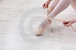 Ballerina puts on pointe ballet shoes, graceful legs