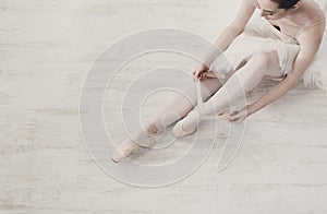 Ballerina puts on pointe ballet shoes, graceful legs