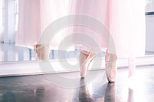 Ballerina`s feet in pointe shoes and pink airy tutu skirt reflecte