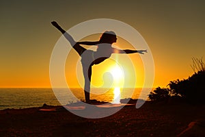 Ballerina silhouette stretching dancing ballet at sunset