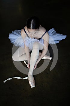 Ballerina sits and wraps pointe shoes