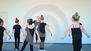 Ballerina and small children jump practicing dance moves