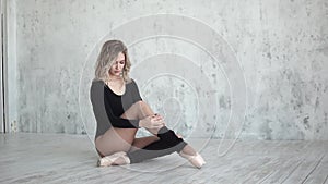 Ballerina spreads leggings sitting on the floor in pointe shoes