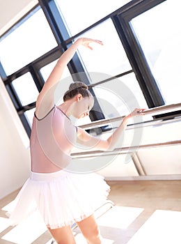 Ballerina Stretching at Barre in Dance Studio