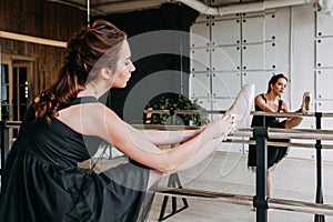 Ballerina stretching leg at barre. Young ballet girl in beautiful dress having ballet practice in studio