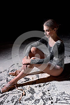 ballerina is tired after work out. lady sitting on floor with flour during ballet classes