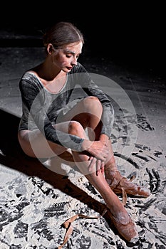 ballerina is tired after work out. lady sitting on floor with flour during ballet classes