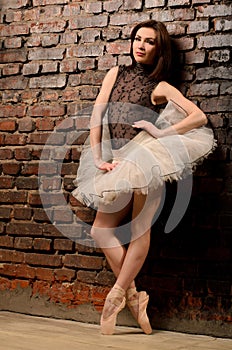 Ballerina in tutu near brick wall