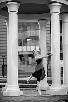 Ballerina in a tutu and pointe shoes makes a beautiful pose. Black and white photo.A beautiful young woman in a black dress is