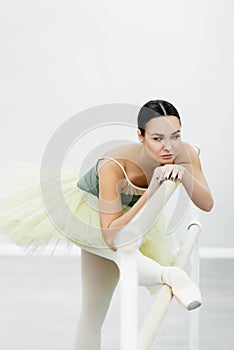 ballerina in tutu stretching at barre