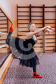 Ballerina Wearing black Tutu Doing exercise in training hall.