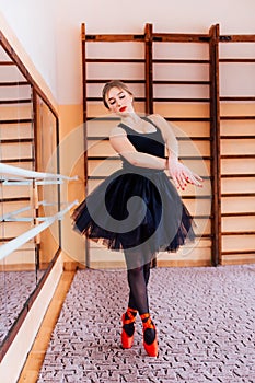 Ballerina Wearing black Tutu Doing exercise in training hall.
