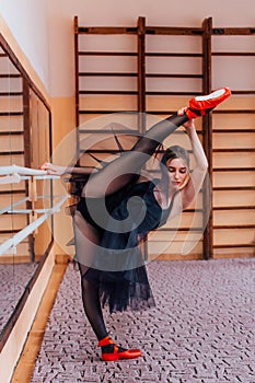 Ballerina Wearing black Tutu make split in training hall.