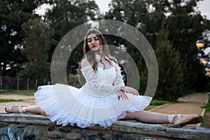 Ballerina wearing white dress and point shoes dancing ballet outdoors