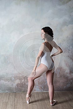 Ballerina in a white bathing suit with a beautiful body standing on pointe shoes