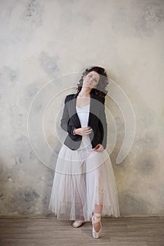 Ballerina in a white bathing suit and of long skirt with a beautiful body standing on pointe shoes