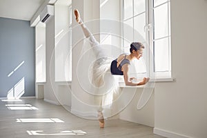 Ballerina. Young graceful ballet dancer is rehearsing a performance in a white studio with windows.