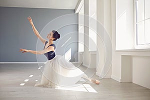 Ballerina. Young graceful ballet dancer is rehearsing a performance in a white studio with windows.