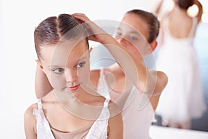 Ballet, children and help with hair in studio, academy or gym, dancer friends training together. Young girl ballerina