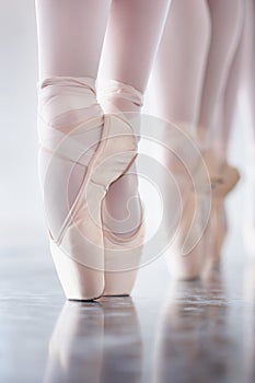 Ballet, dance and shoes with the en pointe feet of a ballerina group in a studio for rehearsal or recital. Creative