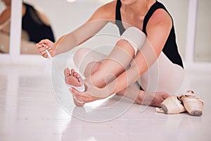 Ballet dancer or ballerina feet getting ready, suffering from sports injury sit on studio floor. Creative artist with