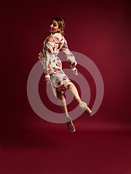 Ballet dancer or classic ballerina dancing isolated on red background. The dance, grace, artist, contemporary, movement, action