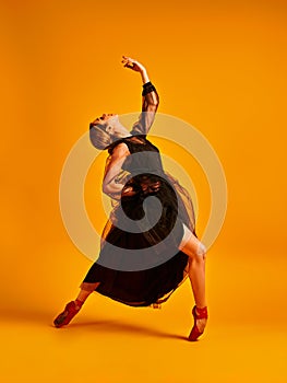 Ballet dancer or classic ballerina dancing isolated on yellow background. The dance, grace, artist, contemporary, movement, action