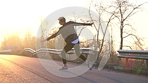 A ballet dancer in the glare of the sun performs a jump of the revoltade, slow motion