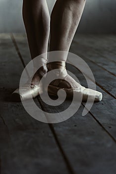 Ballet dancer legs in pointes standing on the black floor