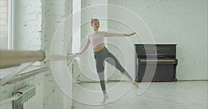 Ballet dancer performing passe exercise at barre