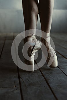 Ballet dancer standing on the tiptoes in the black room