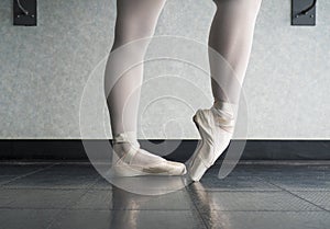 Ballet dancer warming up her feet in her pointe shoes for ballet class
