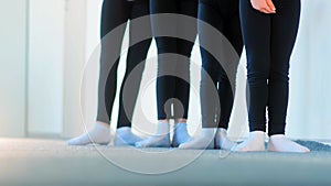 Ballet dancers in black tracksuits exercise stretching legs