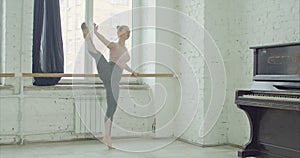 Ballet dancers practicing adagio exercise at barre