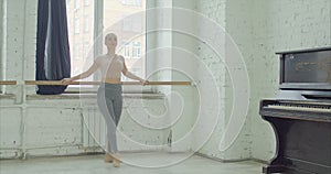 Ballet dancers practicing grand battement at barre