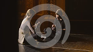 Ballet dancers sit on theater stage eating dinner