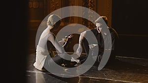 Ballet dancers sit on theater stage eating dinner