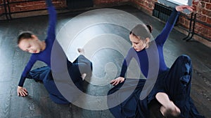 Ballet dancing indoors - two ballerina girls synchronously dancing in the studio in long dresses